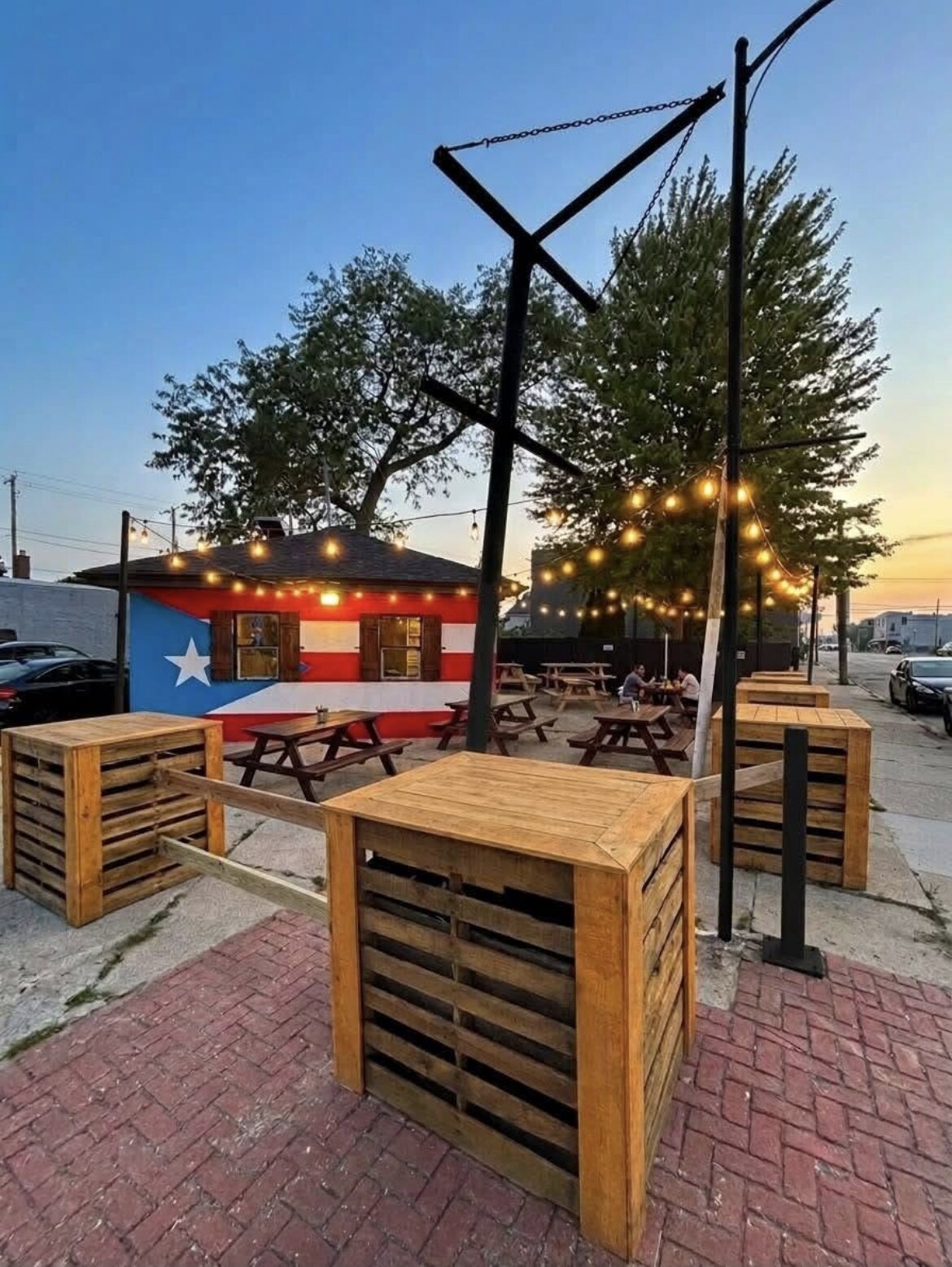 El Batey patio at sunset with Puerto Rican flag mural and string lights